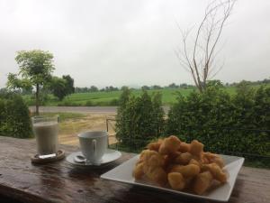 a plate of food on a table with a glass of milk at Baan Tonjaeng Resort in Chai Nat