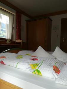 a bed with a white blanket with flowers on it at Gästehaus Waldruh in Mayrhofen