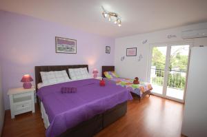 a bedroom with a purple bed and a balcony at Apartment Mlađan in Njivice