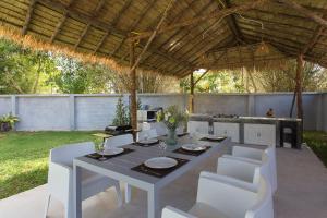 a table with white chairs and a kitchen in a backyard at Baan Intira Pool Villa in Ao Nang Beach