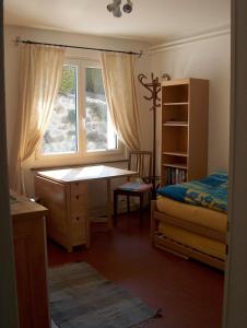 a bedroom with a desk and a bed and a window at Appartement La Coudraie in Blonay
