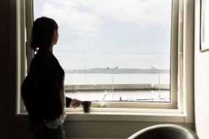 a woman standing in front of a window with a cup at Villa Solviken in Lysekil