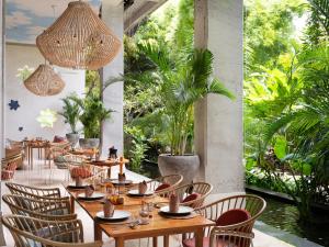 a restaurant with wooden tables and chairs and plants at Amnaya Resort Kuta in Kuta