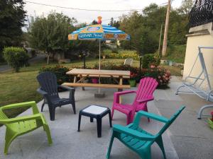 a group of chairs and a picnic table with an umbrella at Gîte de Marie in Burlats