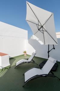 twee witte parasols en twee stoelen en een tafel bij El Solarium de Torre in Cádiz