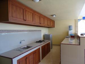 a kitchen with wooden cabinets and a sink and a refrigerator at Putu Guest House 2 in Canggu