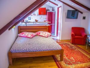 a small bedroom with a bed and a red chair at Old town apartmant in Dubrovnik