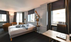 a bedroom with a bed and a desk and windows at Residentie De Laurier in Knokke-Heist