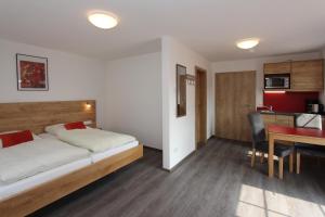 een slaapkamer met een bed, een bureau en een keuken bij Döllelhof Erding in Erding