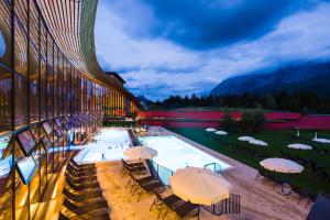 a building with a pool with umbrellas and chairs at Aldiana Club Salzkammergut und GrimmingTherme in Bad Mitterndorf