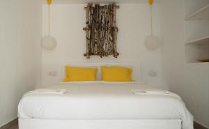 a bedroom with a white bed with two yellow pillows at Casa de la Mare in Vama Veche