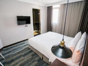 a hotel room with a bed and a flat screen tv at Khan Hotel in Kaohsiung