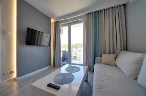 a living room with a couch and a table at Sea Apartment Leśne Tarasy in Dziwnówek