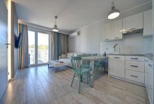 a kitchen and living room with a table and chairs at Sea Apartment Leśne Tarasy in Dziwnówek