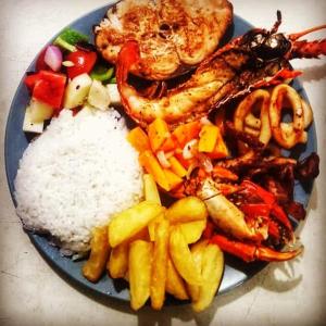 a plate of food with rice and seafood and vegetables at Kilwa Beach Lodge in Kilwa Masoko