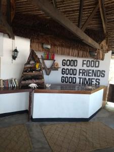 un restaurante con un cartel que lee buena comida buenos amigos buenos tiempos en Kilwa Beach Lodge en Kilwa Masoko