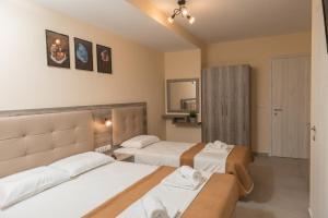 a hotel room with two beds and a mirror at INO Luxury Rooms in Paralia Katerinis