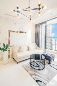 ein Wohnzimmer mit einem weißen Sofa und einem Tisch in der Unterkunft Vinhomes Premium Apartment in Ho-Chi-Minh-Stadt