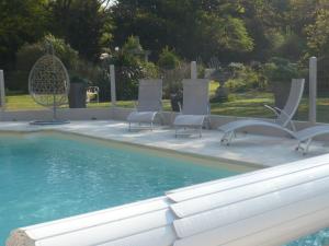 a swimming pool with two chairs and a table at La Petite Ferme in Vouzeron +47 photos