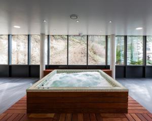 uma grande banheira de hidromassagem num quarto com janelas em Le Parc Des Fees Hôtel Retaurant & Spa em La Bourboule