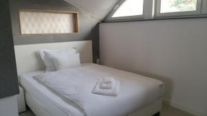 a small bedroom with a white bed and two windows at House-Cora in Stare Miasto