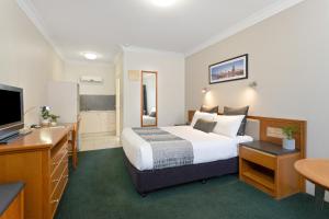 a hotel room with a bed and a desk at Coopers Colonial Motel in Brisbane