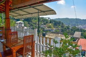 a wooden table and chairs on a balcony with a view at Satyodaya Educational Training Centre in Kandy