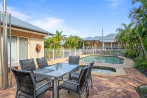 um pátio com uma mesa e cadeiras ao lado de uma piscina em Coopers Colonial Motel em Brisbane