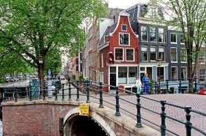 een brug over een kanaal in een stad met gebouwen bij COMMUNE suites in Amsterdam
