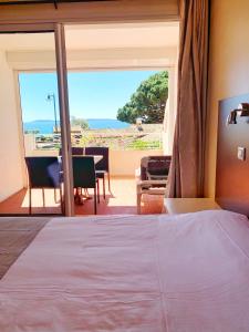 a bedroom with a bed and a view of the ocean at Hôtel Beau Soleil in Le Lavandou