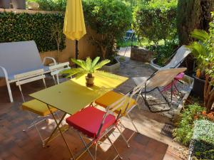 マンドリュー・ラ・ナプールにあるGrand 2 pièces plain pied avec jardin et terrasseのパティオ(テーブル、椅子、黄色の傘付)