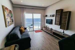 uma sala de estar com um sofá e uma televisão em Seafront Apartment No 10 Marsalforn em Marsalforn