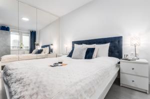 a white bedroom with a large bed with a mirror at Apartments Golden Warsaw by Noclegi Renters in Warsaw