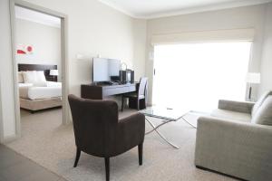 a living room with a bed and a desk with a chair at Centrepoint Apartments Griffith in Griffith