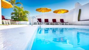 a swimming pool with two umbrellas and chairs at Bull Astoria in Las Palmas de Gran Canaria