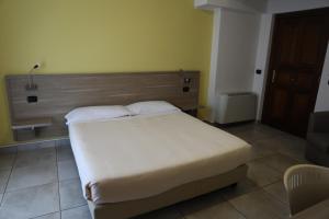 a bedroom with a white bed with a wooden headboard at Garnì House Majorana in Rende