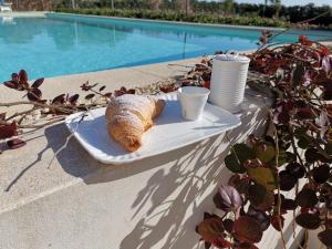 un piatto con cornetto e tazze su un tavolo a bordo piscina di Melus Maris a Siracusa