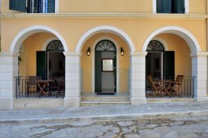 a building with arches and a door and tables at Milonas Studios in Corfu