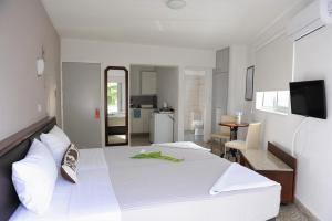 a bedroom with a white bed and a kitchen at Napa City Apartments in Ayia Napa