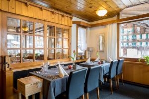 un comedor con mesas, sillas y ventanas en Hotel Restaurant Urweider, en Innertkirchen