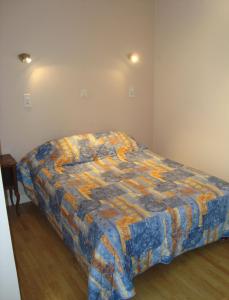 a bedroom with a bed with a colorful quilt at Splendid Hôtel in Montreuil-Bellay