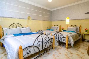 Un dormitorio con dos camas con sábanas azules y blancas. en Hôtel Faouzi, en Marrakech
