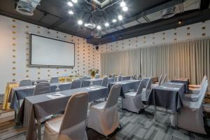 una sala de conferencias con mesas y sillas y una pantalla de proyección en DARA Hotel - SHA Plus en Phuket