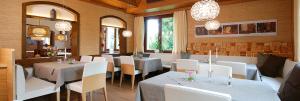 restauracja z białymi stołami, białymi krzesłami i żyrandolami w obiekcie Gasthof Birkenhof w mieście Althütte