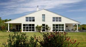 una casa bianca con grandi finestre su un campo di La Villa Blanche - 18 personnes a Pénestin