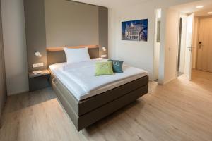 - une chambre avec un grand lit et des draps blancs dans l'établissement Motel B, à Bocholt