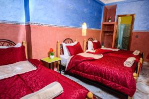 1 dormitorio con 2 camas con sábanas rojas en Hôtel Faouzi, en Marrakech