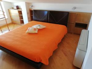 sypialnia z dużym pomarańczowym łóżkiem z 2 poduszkami w obiekcie Attico "Elisa" Vista Mare w mieście Porto Torres
