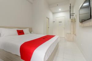 a white bedroom with a red blanket on a bed at RedDoorz Apartment @ Dramaga Tower in Bogor