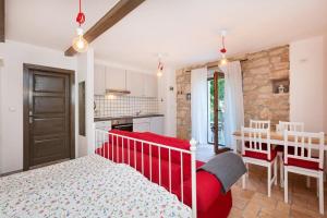 a bedroom with a red bed and a kitchen at Old town studio and apartment in Vrsar